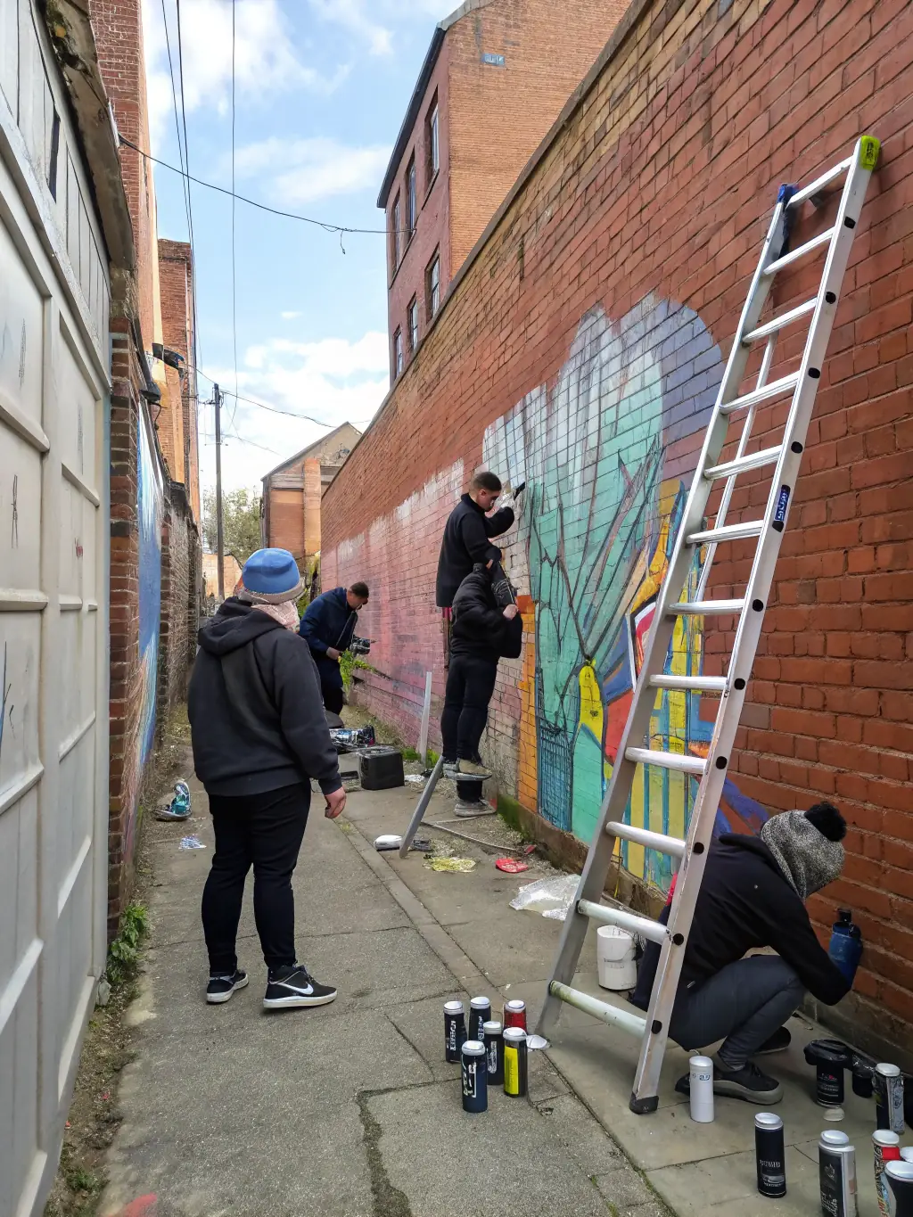 A photograph capturing a diverse group of artists collaborating on a large-scale mural in an urban setting, showcasing community engagement and artistic expression.
